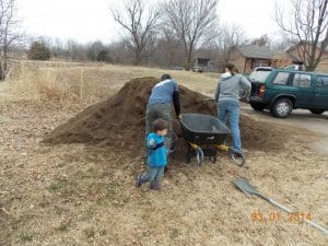 family helping fill garden beds with soil