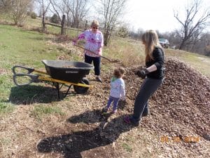 families filling wheel barrow with rocks for preschool garden 