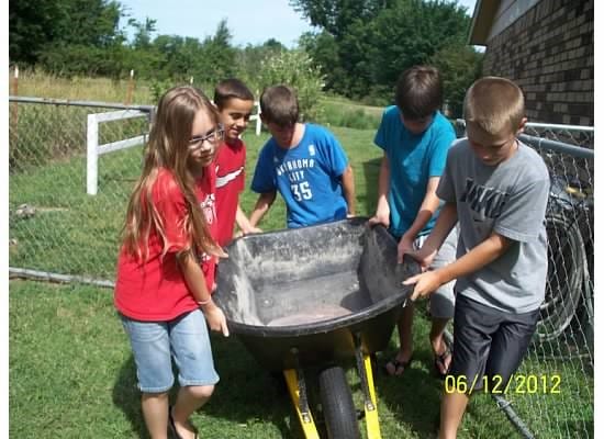 kids working together to move wheelbarrow in a children's garden