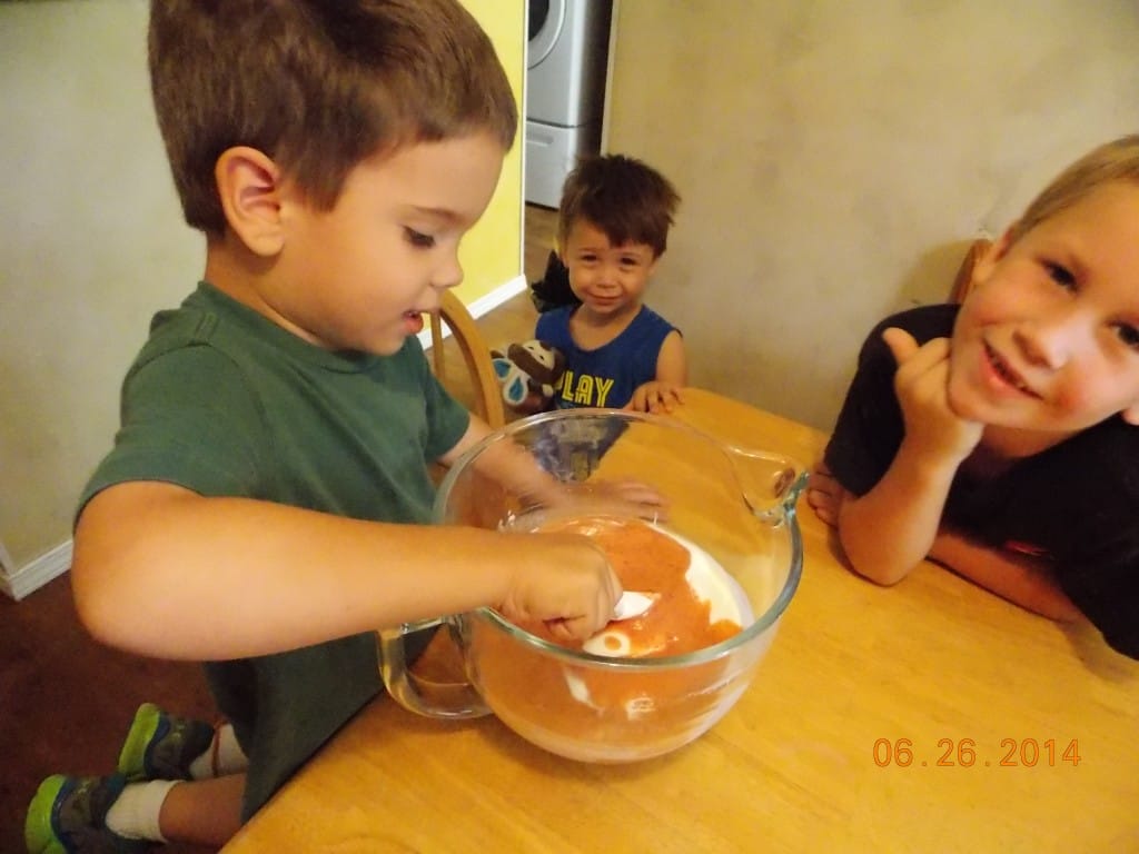 kids stirring pureed peaches into yogurt 