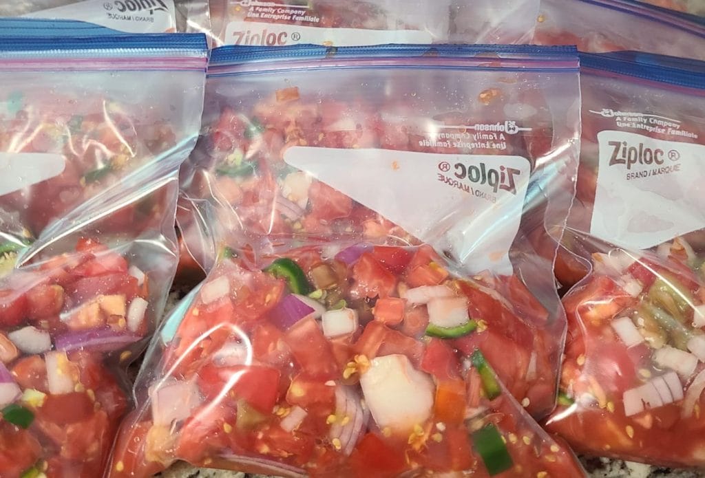 Bags of homemade rotel tomatoes ready to freeze lined up on the counter