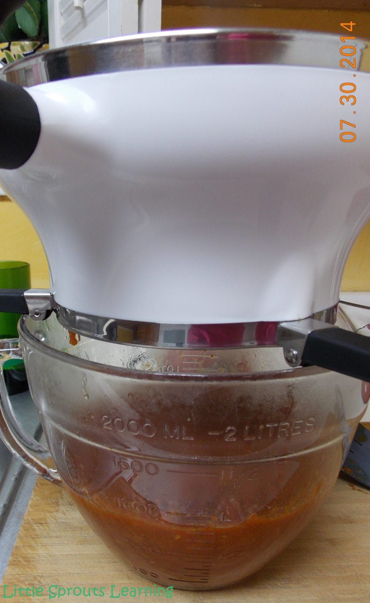food mill on a bowl with roasted tomato sauce going in