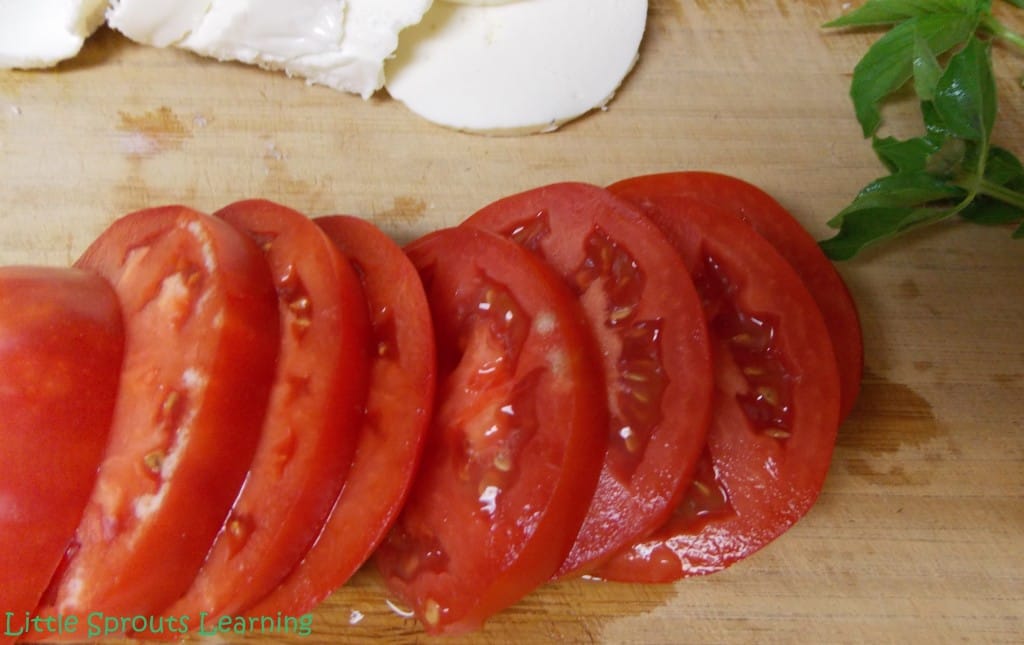 Beautifully sliced heirloom tomatoes placed on a cutting board with slices of fresh mozzarella. 