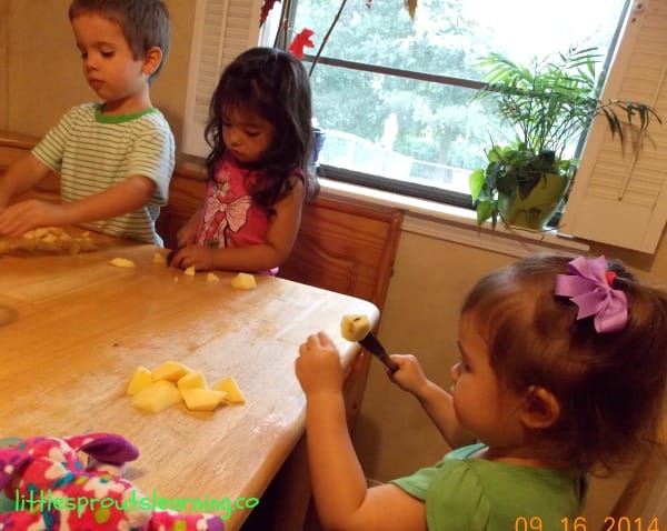children using butterknives to cut apples into chunks