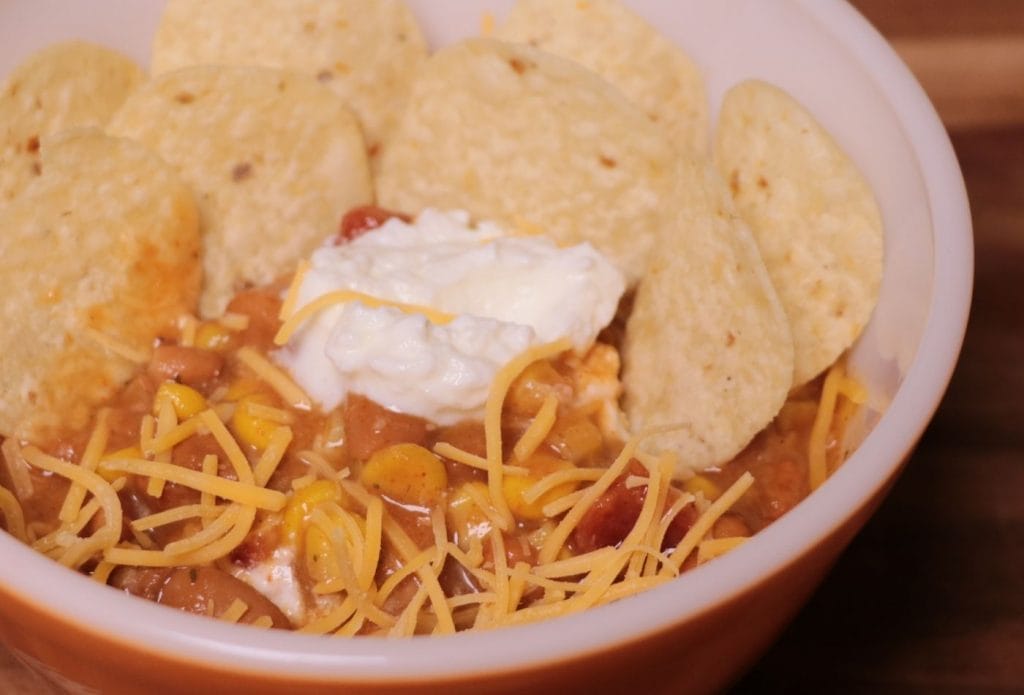 bowl of taco soup topped with tortilla chips, sour cream, and shredded cheese