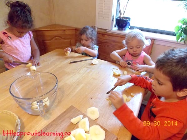 kids cutting chunks of apples with a butter knife at the table