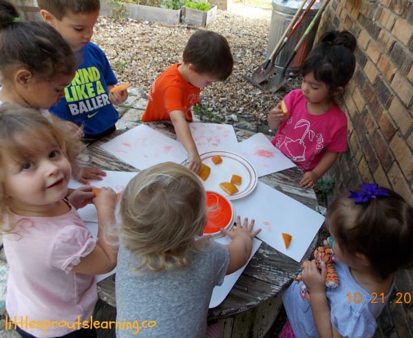 Kids doing pumpkin stamp art on a table outside