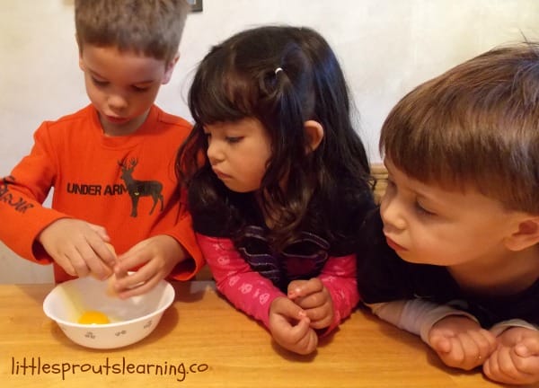 kids cracking eggs in a bowl