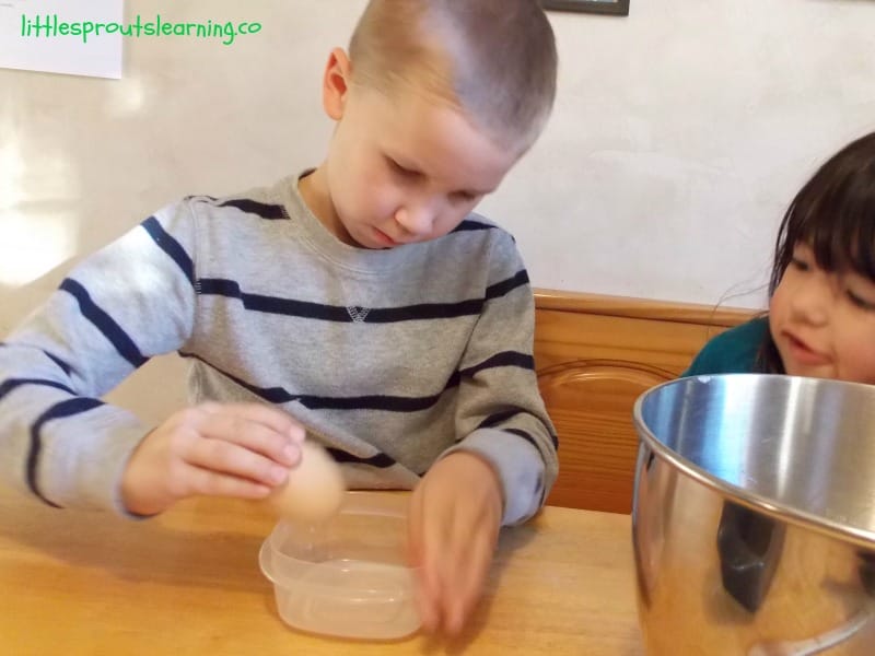 child cracking egg on side of bowl.