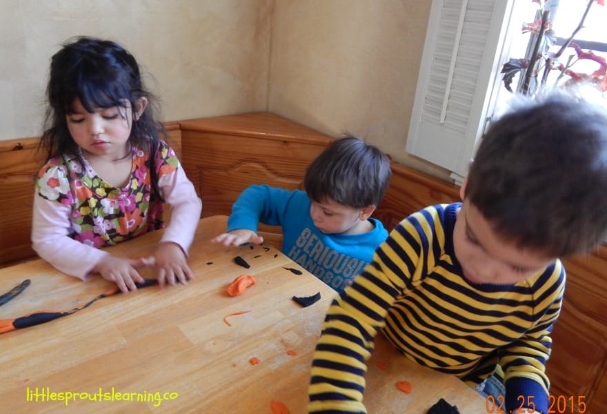 young kids playing with playdough at the table