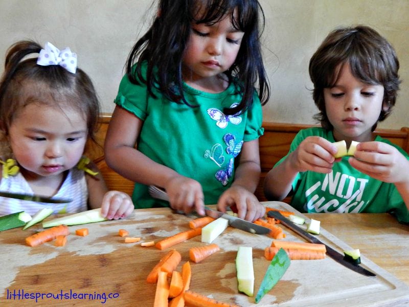 kids cooking at the table cutting up veggies