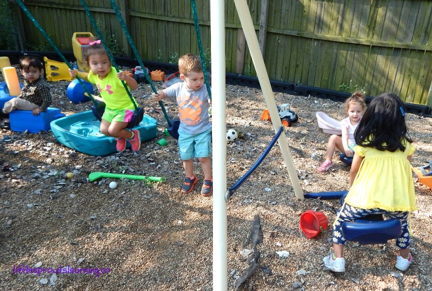 outside play, a child sitting on a toy, two on swings and two on a teeter totter