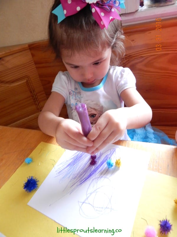 child using pom poms and glitter pens on different kinds of paper.