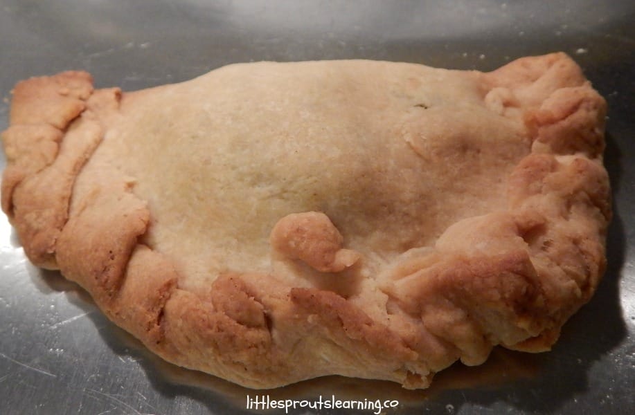 crispy flaky sausage and potato empanada on a tray.