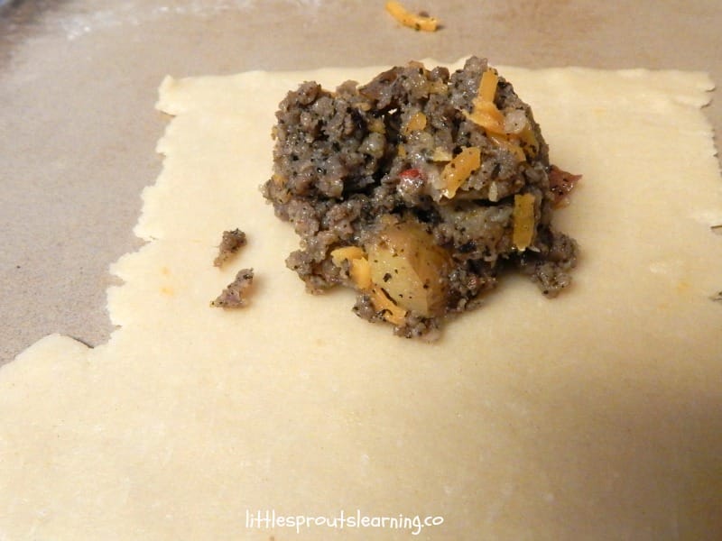 stuffing empanada dough with sausage, cheese, and potato empanadas
