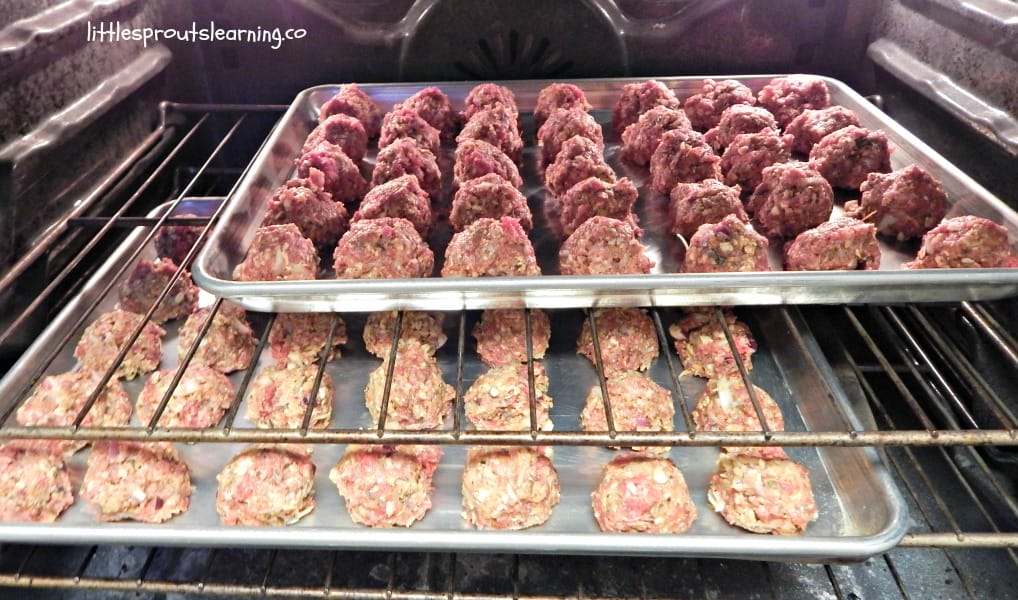Homemade meatballs baking in the oven on two sheet trays