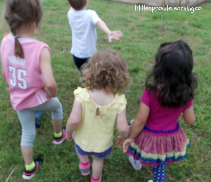 children walking on the grass across the yard holding hands in family child care