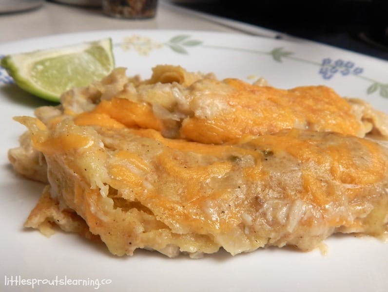 two chicken enchiladas on a plate with lemon wedge