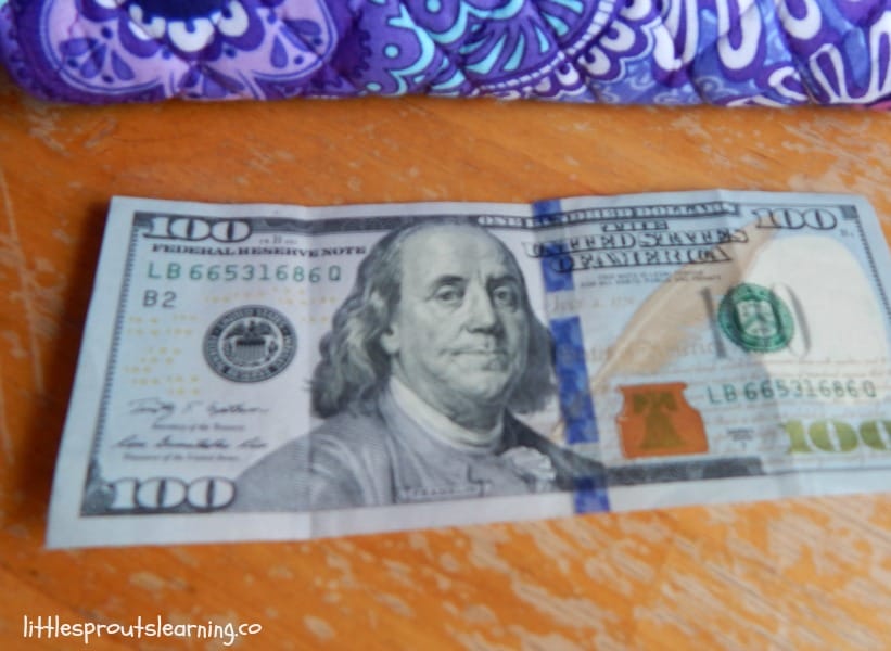 hundred dollar bill and wallet on table