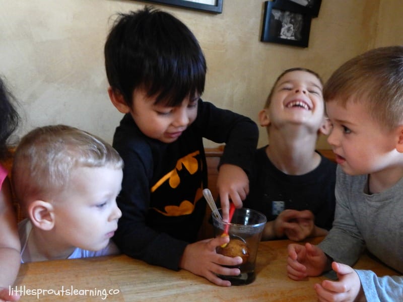 kids trying to brush an egg stained with soda with a toothbrush to clean it
