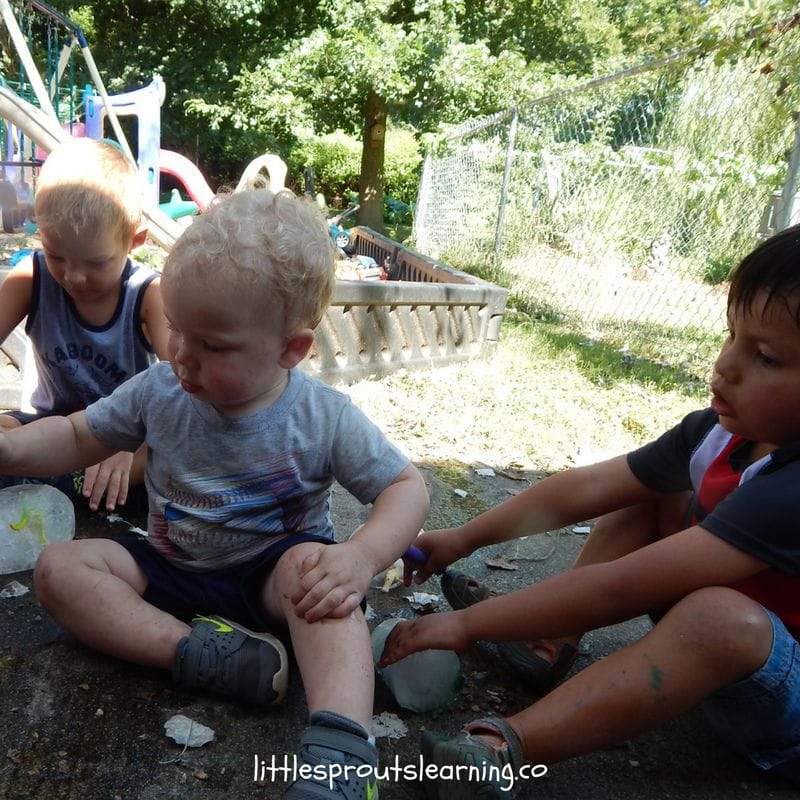 Kids sitting on the porch thawing glaciers with frozen plastic dinosaurs