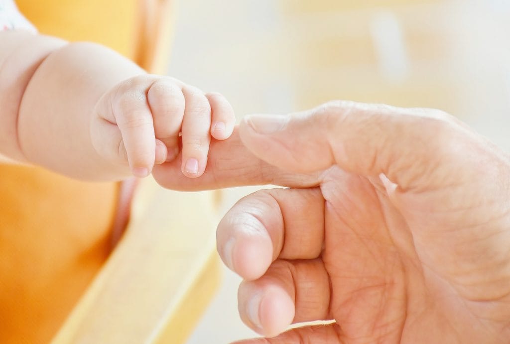 Baby holding adult finger