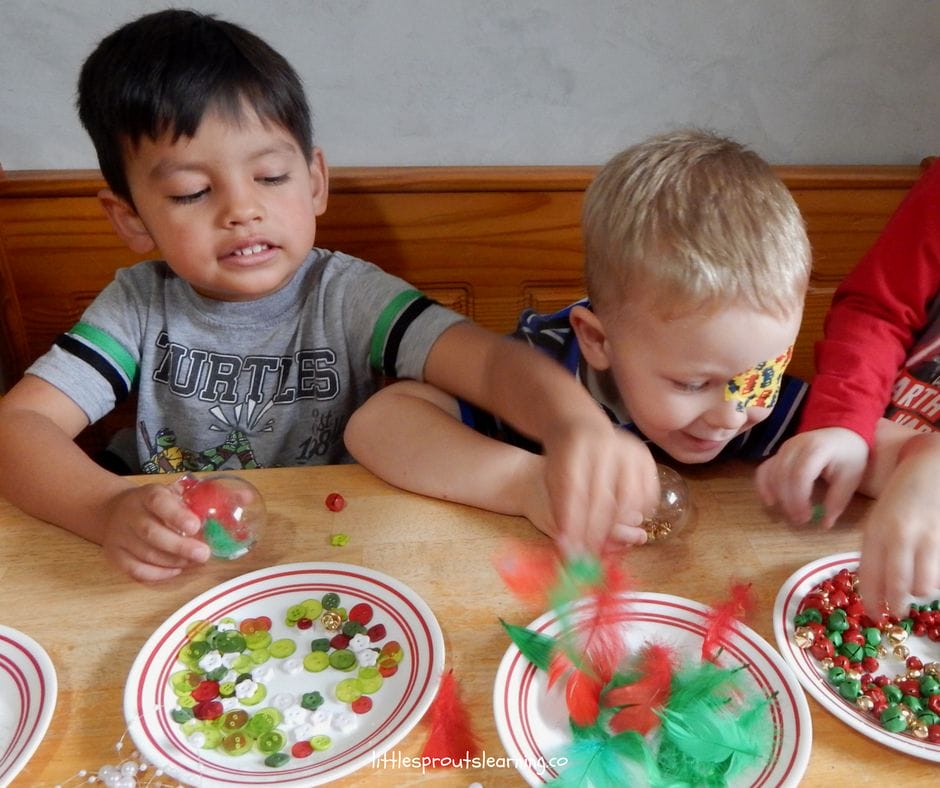 kids stuffing clear ornaments with pretty decorations like feathers, buttons, and tiny bells