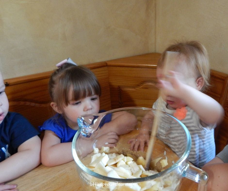 kids stirring apple crisp ingredients at the table and learning cooking skills for kids.