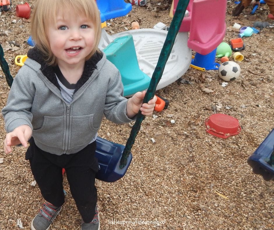 confident kid sitting on swing on the playground, building self-esteem