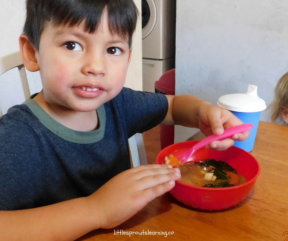 boy at the table enjoying friendship soup he made with his friends.