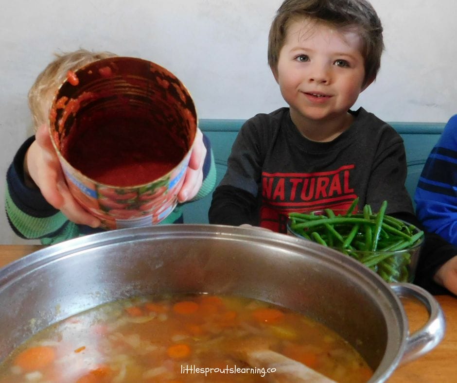 Kids adding vegetables they brought from home to friendship soup