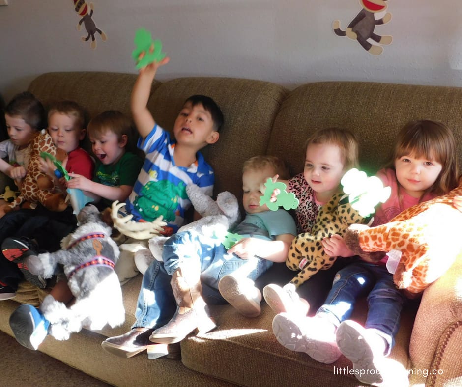 kids sitting on the couch playing with stuffed animals and frog finger puppets.