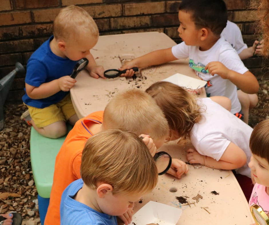 Kids observing worms and compost under magnifying glass