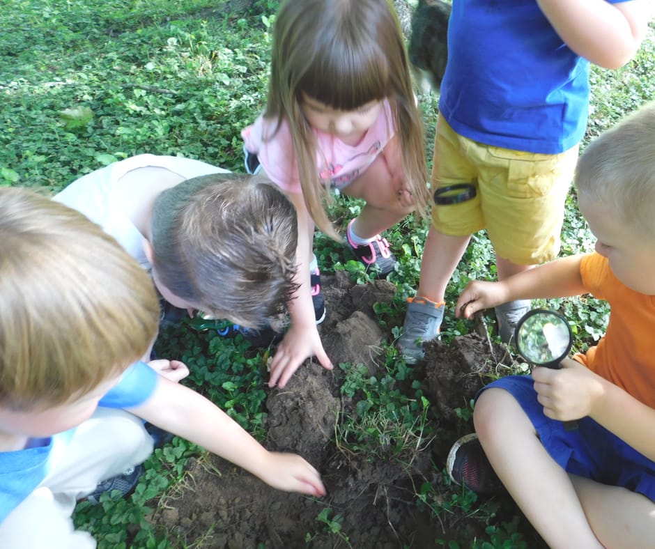 kids exploring soil with magnifying glasses
