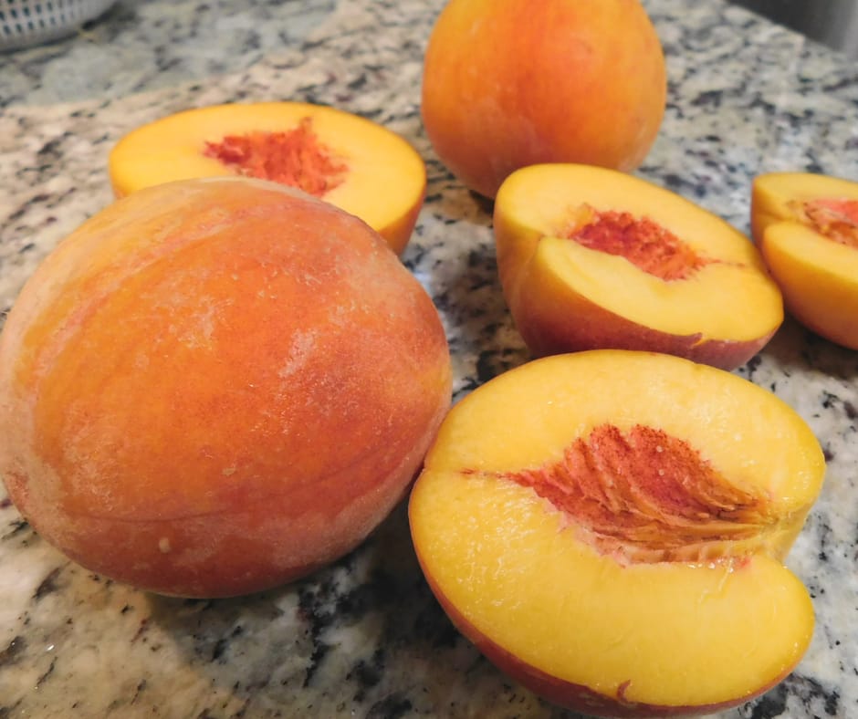 peaches on the counter, some whole and some cut in half