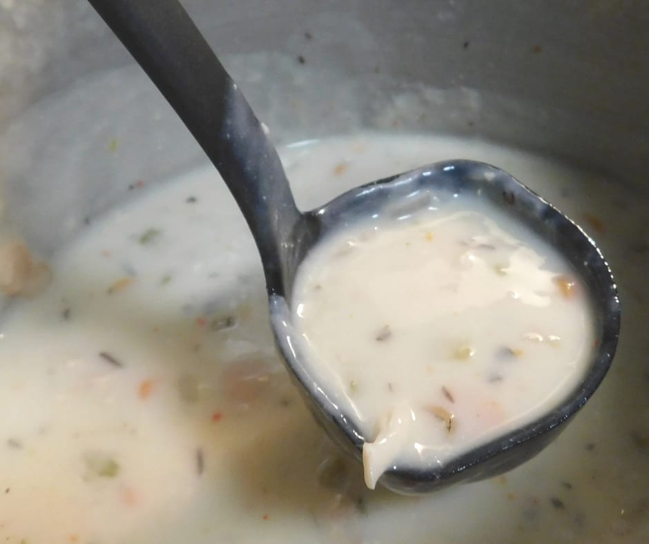 Pot of Panera Copycat Instant Pot Chicken and Wild Rice Soup with a ladel full coming out.