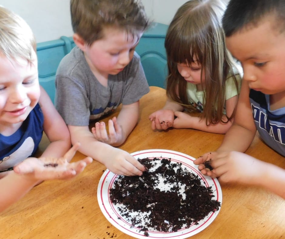 Kids exploring worms and garden soil at the table
