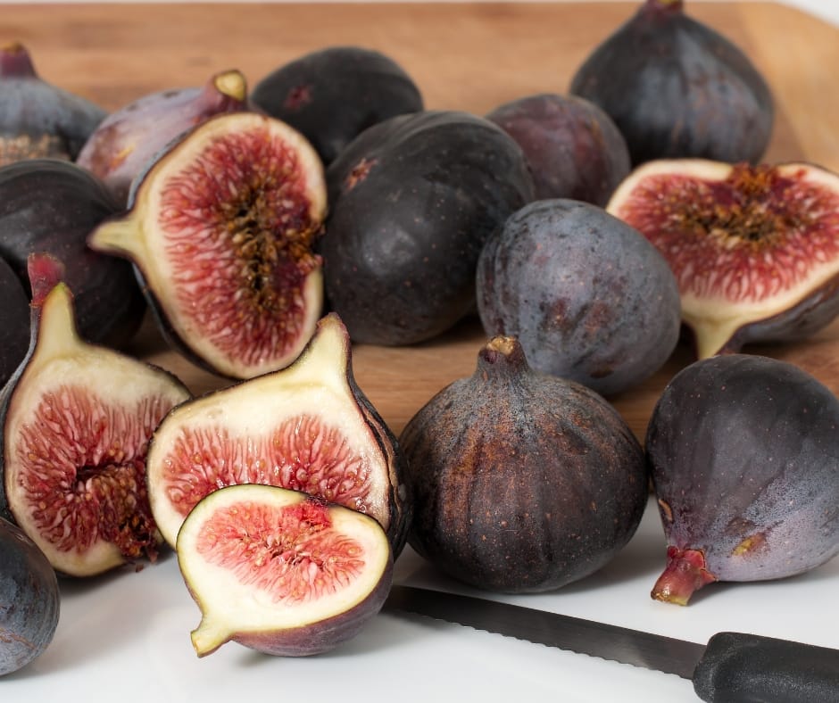 Cutting board full of brown figs cut in half