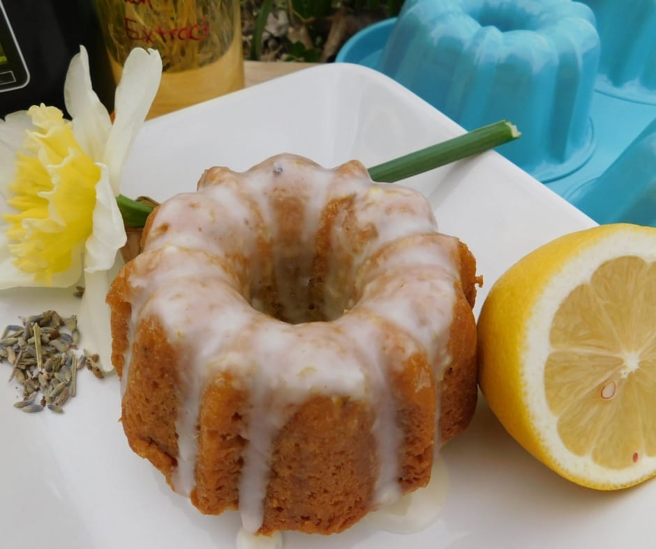 honey lavender cake on a plate with a daffodil and a half a lemon. The cake is drizzled with glaze