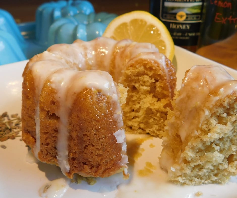 honey lavender bundt cake with glaze, a piece cut out on a plate wtih lemon behind
