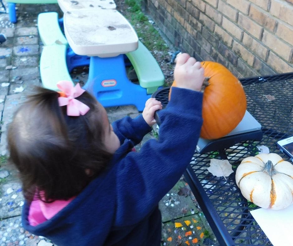 child weighing pumpkin on scale for pumpkin activities