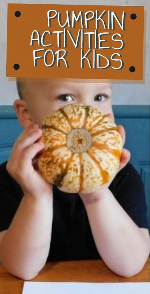 young child holding a small pumpkin up 