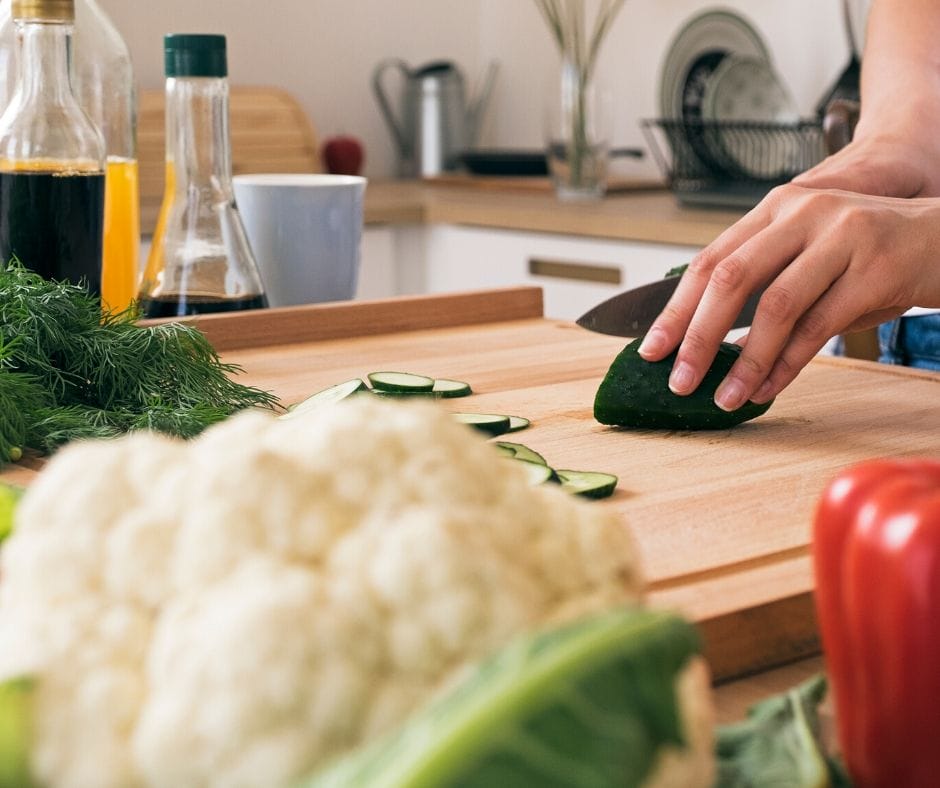 Cucumber being cut on a cutting board.