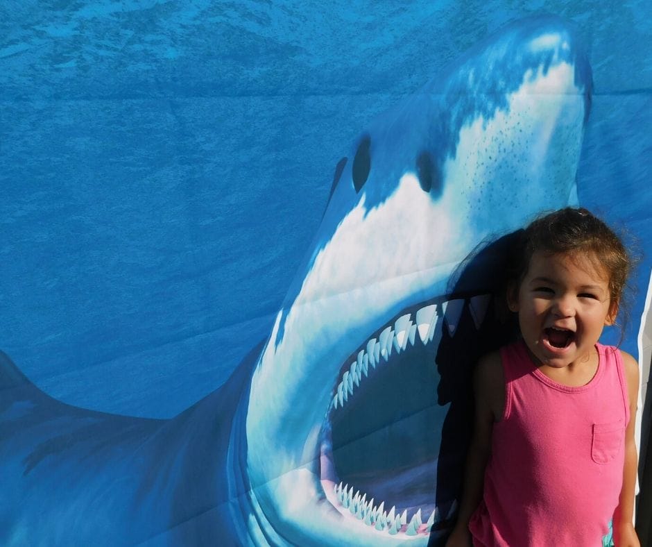 child pretending to be eaten by shark picture for photo op at shark party