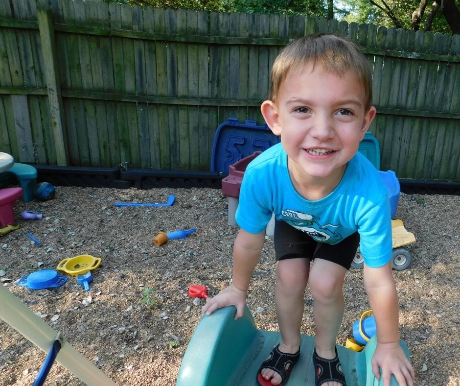 child smiling on the top of a slide