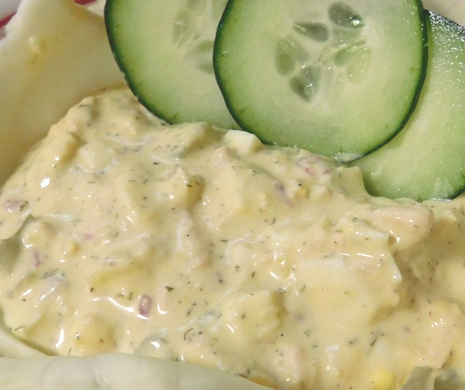 tuna salad in a lettuce bowl with cucumber slices. 