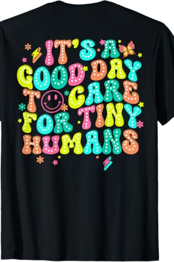 Black T-shirt with colorful text saying, "It's a good day to care for tiny humans," perfect for those passionate about child care. Decorated with smiley faces, stars, and lightning bolts, this tee combines style and a love for nurturing little ones.