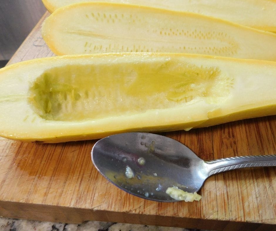 yellow squash with center scooped out with a spoon on a cutting board