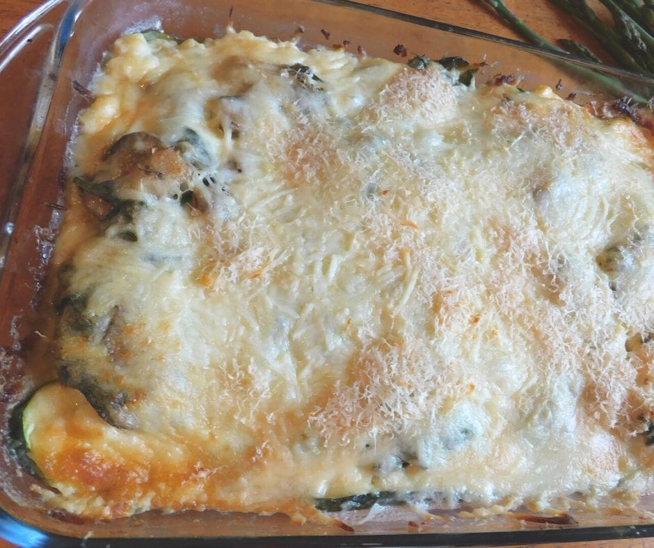 Nightshade free vegetable lasagna in a pan showing melty cheese and a few green veggies peeking through