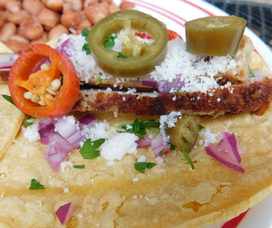 Pork chop tacos close up showing pork chops, onions, hot peppers, cotija cheese and cilantro.